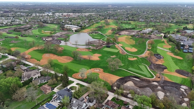 Aerial view of a golf course under renovation with green fairways and sand traps surrounded by residential houses and lush trees in Chicago. Aerial view of a golf course under renovation with green fairways and sand traps surrounded by residential houses and lush trees in Chicago.