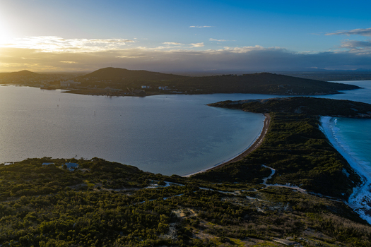 Aerial view of Camp Quaranup on the Vancouver Peninsula featuring coastal vegetation turquoise bay waters and rolling hills at sunset in Vancouver Peninsula Western Australia Australia. Aerial view of Camp Quaranup on the Vancouver Peninsula featuring coastal vegetation turquoise bay waters and rolling hills at sunset in Vancouver Peninsula Western Australia Australia.