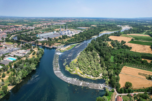 Aerial view of Parco Fluviale del Bricel with the Po river surrounding lush greenery agricultural fields and a nearby industrial power plant in Chivasso Piemonte Italy. Aerial view of Parco Fluviale del Bricel with the Po river surrounding lush greenery agricultural fields and a nearby industrial power plant in Chivasso Piemonte Italy.