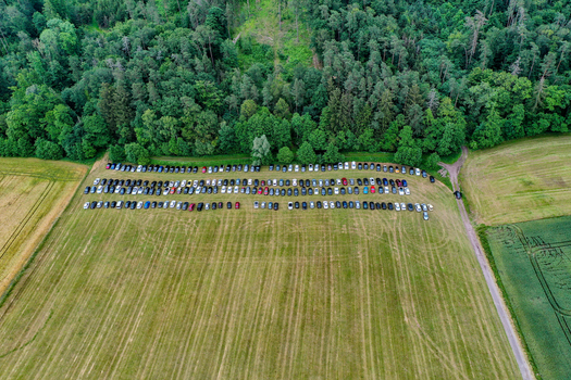 Aerial view of rows of cars parked in a grassy field next to a lush green forest at the Heroes Festival Geiselwind Bayern Germany.