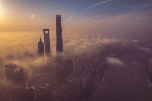 Aerial view of the Lujiazui financial district skyscrapers including the Shanghai Tower emerging from a thick layer of morning fog at sunrise in Shanghai Shanghai China.
