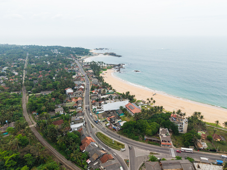 Aerial view of the coastal road and railway line running alongside a sandy beach and turquoise ocean in Dodanduwa Southern Province Sri Lanka. Aerial view of the coastal road and railway line running alongside a sandy beach and turquoise ocean in Dodanduwa Southern Province Sri Lanka.