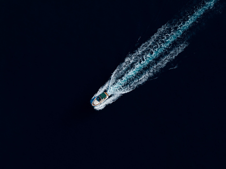 Aerial view of a motorboat cruising through the dark blue Mediterranean Sea leaving a white wake near the coast of Le Trayas in Saint Raphael Provence Alpes Cote d Azur France. Aerial view of a motorboat cruising through the dark blue Mediterranean Sea leaving a white wake near the coast of Le Trayas in Saint Raphael Provence Alpes Cote d Azur France.