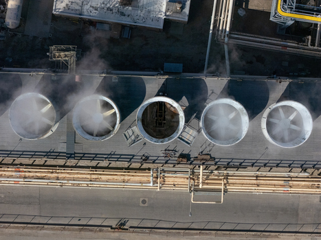 Aerial view of industrial cooling fans with steam rising from the vents at a facility in Carson California United States.