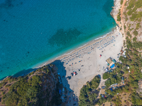Aerial view of Gjipe Beach with turquoise waters sandy shore sun loungers and surrounding cliffs in Vlore County Albania. Aerial view of Gjipe Beach with turquoise waters sandy shore sun loungers and surrounding cliffs in Vlore County Albania.