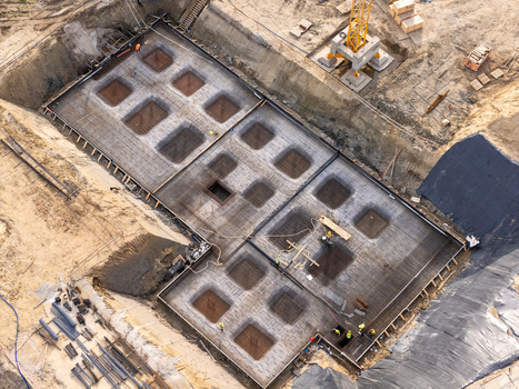 Aerial view of a construction site foundation with steel rebar reinforcement grids and concrete formwork with construction workers visible on the ground in Gdansk Poland. Aerial view of a construction site foundation with steel rebar reinforcement grids and concrete formwork with construction workers visible on the ground in Gdansk Poland.