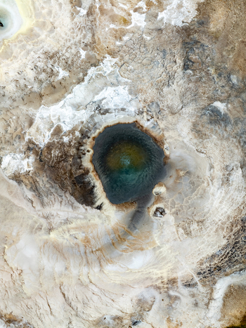 Aerial view of the Hveravellir geothermal pool with vibrant blue and green water surrounded by mineral deposits and rugged volcanic terrain Hunabyggd Iceland.