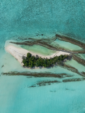 Aerial view of a lush island with white sand vibrant turquoise waters and dark reefs Thuraakunu Thiladhunmathee Uthuruburi Maldives. Aerial view of a lush island with white sand vibrant turquoise waters and dark reefs Thuraakunu Thiladhunmathee Uthuruburi Maldives.