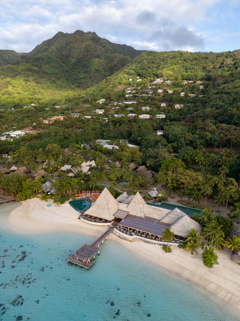 Aerial view of Sofitel Kia Ora Moorea Beach Resort with its wooden pier white sand beach and lush green mountains in Moorea Maiao Windward Islands French Polynesia. Aerial view of Sofitel Kia Ora Moorea Beach Resort with its wooden pier white sand beach and lush green mountains in Moorea Maiao Windward Islands French Polynesia.
