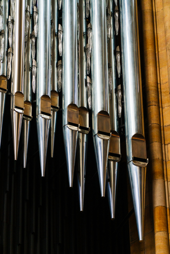 View of metallic pipe organ pipes mounted against a stone wall in a church interior in Prague Prague Czechia.