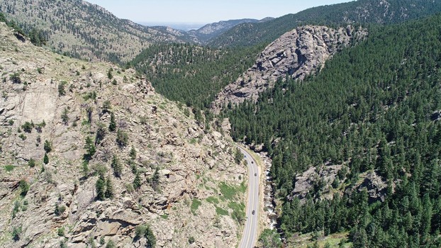 Aerial view of the Bihedral Trail Head area in Boulder Canyon featuring a winding mountain road rocky cliffs dense pine forests and a flowing stream in Nederland Colorado United States. Aerial view of the Bihedral Trail Head area in Boulder Canyon featuring a winding mountain road rocky cliffs dense pine forests and a flowing stream in Nederland Colorado United States.
