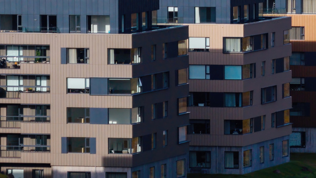 Aerial view of a modern apartment complex with metallic cladding and large windows in Iceland. Aerial view of a modern apartment complex with metallic cladding and large windows in Iceland.