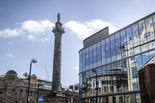 View of Grey s Monument in the city center surrounded by historic stone buildings and a modern glass structure reflecting the surroundings in Newcastle upon Tyne England United Kingdom. View of Grey s Monument in the city center surrounded by historic stone buildings and a modern glass structure reflecting the surroundings in Newcastle upon Tyne England United Kingdom.