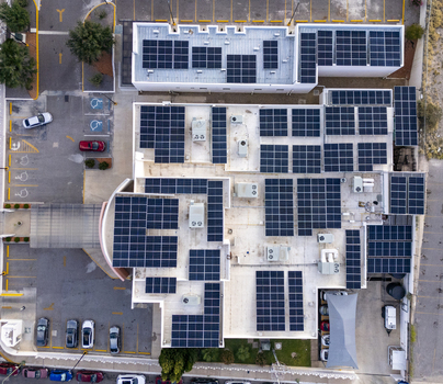 Aerial view of a large solar panel array installed on the flat roof of a commercial building with a parking lot below in Chihuahua Chihuahua Mexico. Aerial view of a large solar panel array installed on the flat roof of a commercial building with a parking lot below in Chihuahua Chihuahua Mexico.