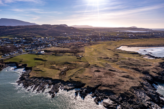 Aerial view of the rugged coastline sandy beach and green fields surrounding the village under bright sunlight in Portnablagh County Donegal Ireland. Aerial view of the rugged coastline sandy beach and green fields surrounding the village under bright sunlight in Portnablagh County Donegal Ireland.
