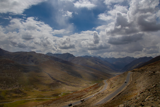 View of the winding road leading towards Nanga Parbat surrounded by the rugged mountain landscape of the Gilgit region under a dramatic cloudy sky in Fairy Meadow Gilgit Pakistan. View of the winding road leading towards Nanga Parbat surrounded by the rugged mountain landscape of the Gilgit region under a dramatic cloudy sky in Fairy Meadow Gilgit Pakistan.