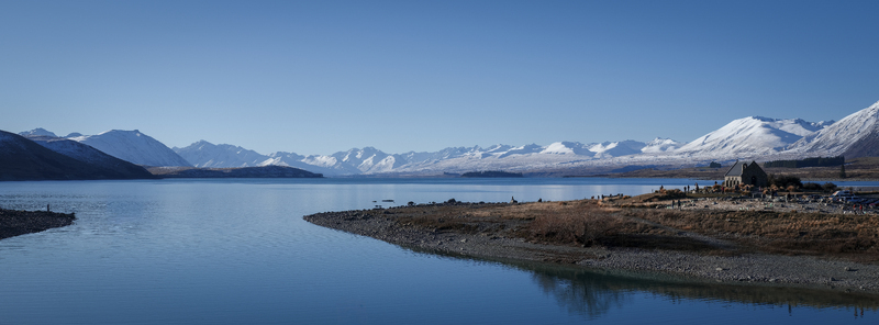 View of the Church of the Good Shepherd on the shores of Lake Tekapo with snow capped mountains in the background under a clear blue sky Lake Tekapo Canterbury Region New Zealand.
