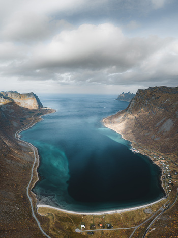 Aerial view of the dramatic fjord landscape of Senja with steep mountains turquoise waters and a small coastal village in Senja Troms Norway.