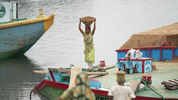 View of a woman carrying sand on her head on a boat Bangladesh. View of a woman carrying sand on her head on a boat Bangladesh.