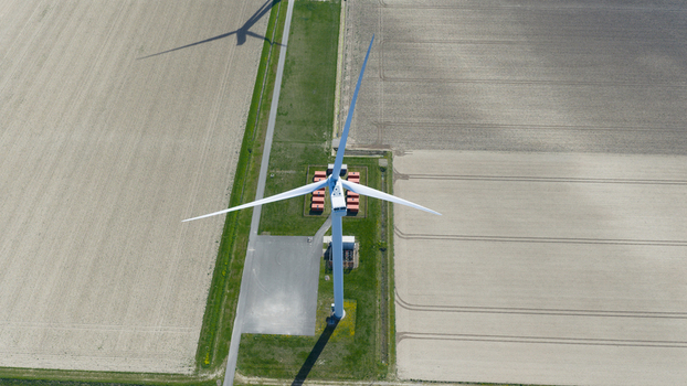 Aerial view of Energiepark Haringvliet Zuid with a large wind turbine casting a long shadow over agricultural fields and technical infrastructure Middelharnis South Holland Netherlands.