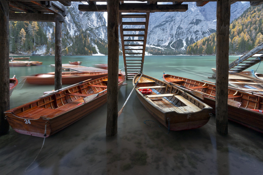 View of wooden rowing boats moored under a boathouse at Pragser Wildsee with turquoise water and the Dolomites in the background Prags Trentino Alto Adige Italy.