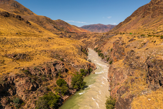 Aerial view of the Chon Kemin river flowing through a deep canyon with golden hills and rocky cliffs in Kemin Chuy Province Kyrgyzstan.