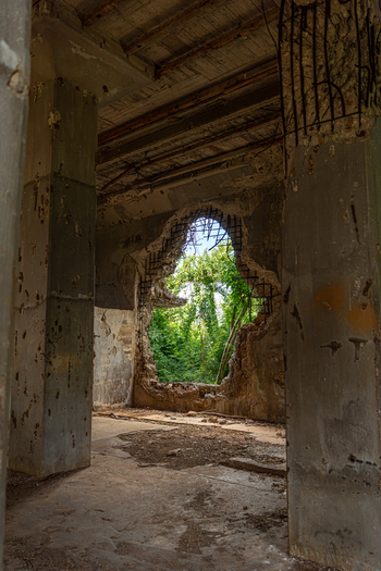 View of weathered concrete ruins of North Field Base with a jagged opening in the wall revealing lush green vegetation in Northern Tinian Tinian Northern Mariana Islands. View of weathered concrete ruins of North Field Base with a jagged opening in the wall revealing lush green vegetation in Northern Tinian Tinian Northern Mariana Islands.