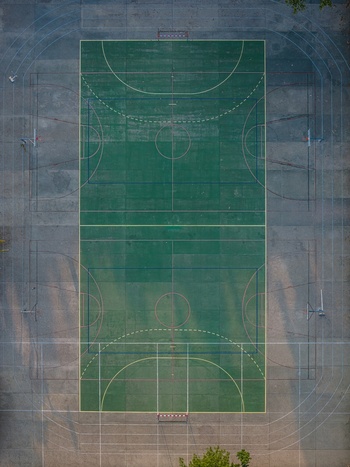 Aerial view of a green multi purpose sports court with basketball hoops and painted lines in Lisbon Portugal.
