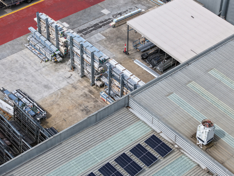 Aerial view of industrial site with metal storage racks solar panels on a corrugated metal roof and industrial machinery in Melbourne VIC Australia.