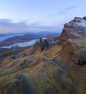 Aerial view of the iconic rock pinnacles of The Storr overlooking the rugged landscape and Loch Leathan under a soft twilight sky Isle of Skye Scotland United Kingdom. Aerial view of the iconic rock pinnacles of The Storr overlooking the rugged landscape and Loch Leathan under a soft twilight sky Isle of Skye Scotland United Kingdom.