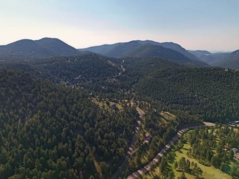 Aerial view of Coal Creek valley surrounded by dense pine forests winding roads and rolling mountain terrain under a clear sky Coal Creek Colorado United States. Aerial view of Coal Creek valley surrounded by dense pine forests winding roads and rolling mountain terrain under a clear sky Coal Creek Colorado United States.
