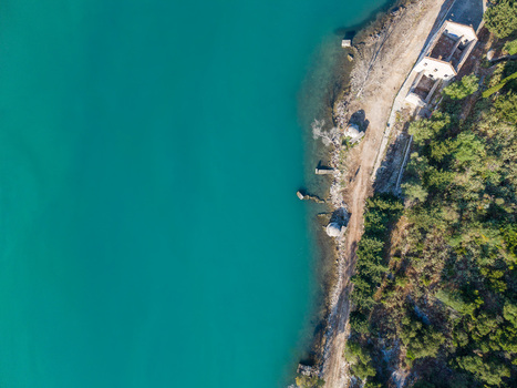 Aerial view of the turquoise waters of Kanali i Vivarit with stone ruins and a dirt path along the shoreline in Vrine Vlore County Albania. Aerial view of the turquoise waters of Kanali i Vivarit with stone ruins and a dirt path along the shoreline in Vrine Vlore County Albania.
