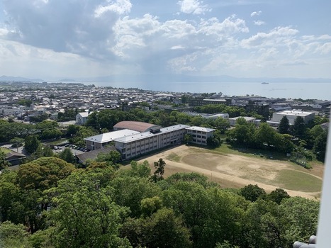 Japan 06 July 2026 View of a school building with a sports field surrounded by lush green trees with a town and a large lake in the background in Japan. Japan 06 July 2026 View of a school building with a sports field surrounded by lush green trees with a town and a large lake in the background in Japan.