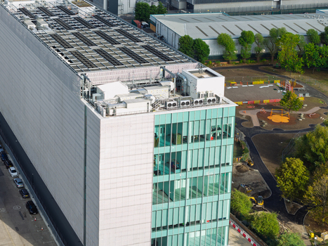 Aerial view of a modern data center building featuring a large rooftop HVAC system and glass facade situated in the United Kingdom. Aerial view of a modern data center building featuring a large rooftop HVAC system and glass facade situated in the United Kingdom.