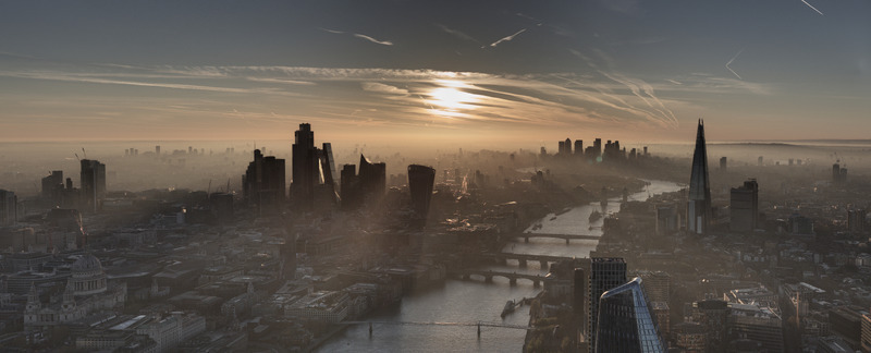 Aerial view of the London skyline featuring the River Thames Blackfriars Bridge and The Shard under a hazy golden sunrise in London Greater London United Kingdom. Aerial view of the London skyline featuring the River Thames Blackfriars Bridge and The Shard under a hazy golden sunrise in London Greater London United Kingdom.