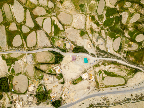 Aerial view of the arid landscape of Zanskar with terraced agricultural fields winding roads and small buildings in the mountainous region of Zanskar Ladakh India.