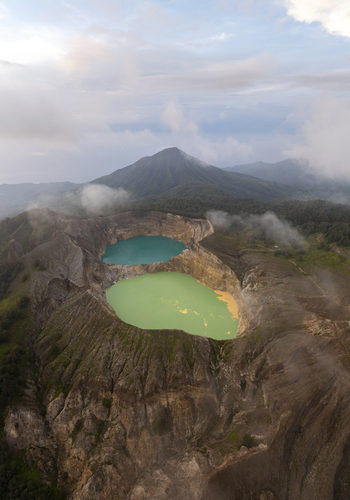 Aerial view of the colorful crater lakes of Kelimutu National Park with volcanic peaks and surrounding lush vegetation in Detusoko East Nusa Tenggara Indonesia.