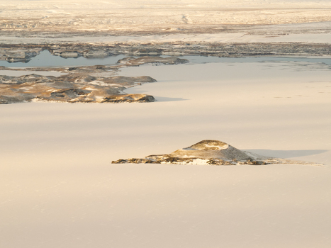 Aerial view of the frozen Myvatn lake with a snow covered volcanic crater island surrounded by vast icy plains in Thingeyjarsveit Iceland. Aerial view of the frozen Myvatn lake with a snow covered volcanic crater island surrounded by vast icy plains in Thingeyjarsveit Iceland.