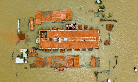 Aerial view of the flooded Baish Mowza Sarak Bazar brick kiln surrounded by murky floodwaters with small wooden boats in Nabinagar Chittagong Division Bangladesh. Aerial view of the flooded Baish Mowza Sarak Bazar brick kiln surrounded by murky floodwaters with small wooden boats in Nabinagar Chittagong Division Bangladesh.