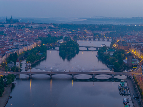 Aerial view of the Vltava River flowing through the historic city center with illuminated bridges and Prague Castle in the distance at twilight in Prague Prague Czechia.