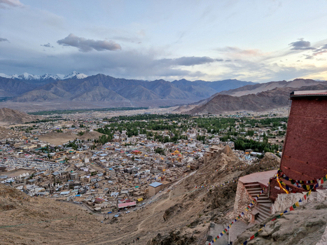 View of Leh Palace overlooking the town of Leh nestled in the Himalayan mountains with prayer flags in the foreground Leh Ladakh India.