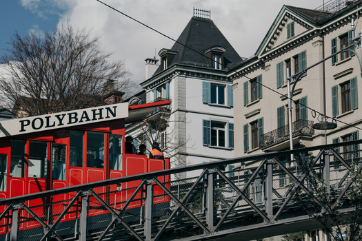 Zurich Switzerland 02 April 2023 View of the bright red Polybahn funicular ascending through the city against a backdrop of elegant buildings and a partly cloudy sky. Zurich Switzerland 02 April 2023 View of the bright red Polybahn funicular ascending through the city against a backdrop of elegant buildings and a partly cloudy sky.