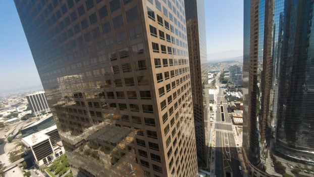 Aerial view of the skyscrapers in Downtown Los Angeles with glass facades reflecting the clear blue sky and city streets below in Los Angeles California United States.