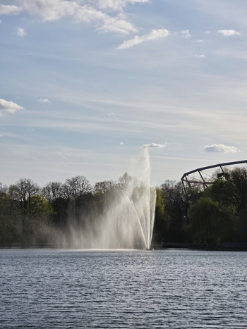 View of the fountain in Maschsee lake with trees and blue sky in the background in Hanover Lower Saxony Germany.