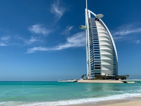 View of the Burj Al Arab hotel standing by the turquoise sea under a clear blue sky with wispy clouds in Dubai Dubai United Arab Emirates. View of the Burj Al Arab hotel standing by the turquoise sea under a clear blue sky with wispy clouds in Dubai Dubai United Arab Emirates.