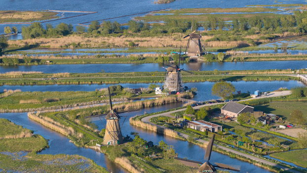 Aerial view of the historic Kinderdijk windmills standing along narrow canals and lush green polders under bright sunlight Kinderdijk South Holland Netherlands. Aerial view of the historic Kinderdijk windmills standing along narrow canals and lush green polders under bright sunlight Kinderdijk South Holland Netherlands.