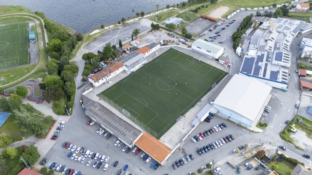 Poio Spain 02 May 2026 Aerial view of Campo de Futbol da Seca surrounded by parking lots industrial buildings and the coastal landscape under bright daylight.