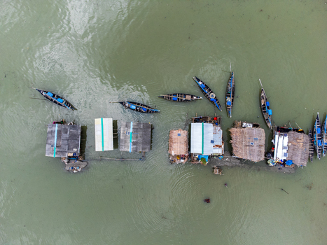 Aerial view of Kalabagi floating village with traditional wooden boats moored next to thatched roof houses on the water Khulna District Khulna Division Bangladesh.