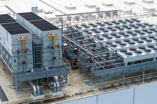 Aerial view of an AI data center cooling system featuring large industrial cooling towers and rows of fans on a rooftop in Krakow Lesser Poland Voivode Poland. Aerial view of an AI data center cooling system featuring large industrial cooling towers and rows of fans on a rooftop in Krakow Lesser Poland Voivode Poland.