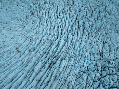 Aerial view of Heinabergsjokull glacier with deep blue crevasses and intricate ice patterns in Sveitarfelagid Hornaf Iceland.